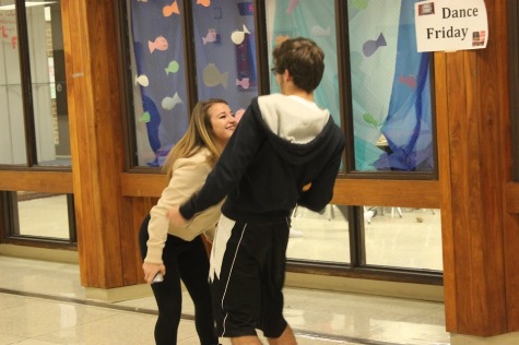 Senior Olgina Gjini and junior James Ebbole dance in the hallway.