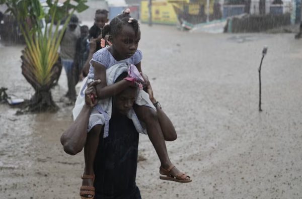 Residents wading through a flooded street after Hurricane Melissa struck Haiti. (Source: OPB News)